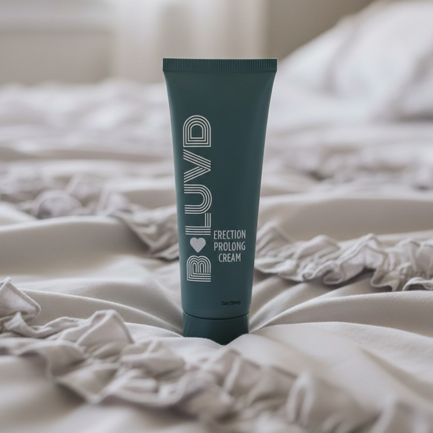 A black bottle of B-Luvd Erection Prolong Cream sitting on a bed.