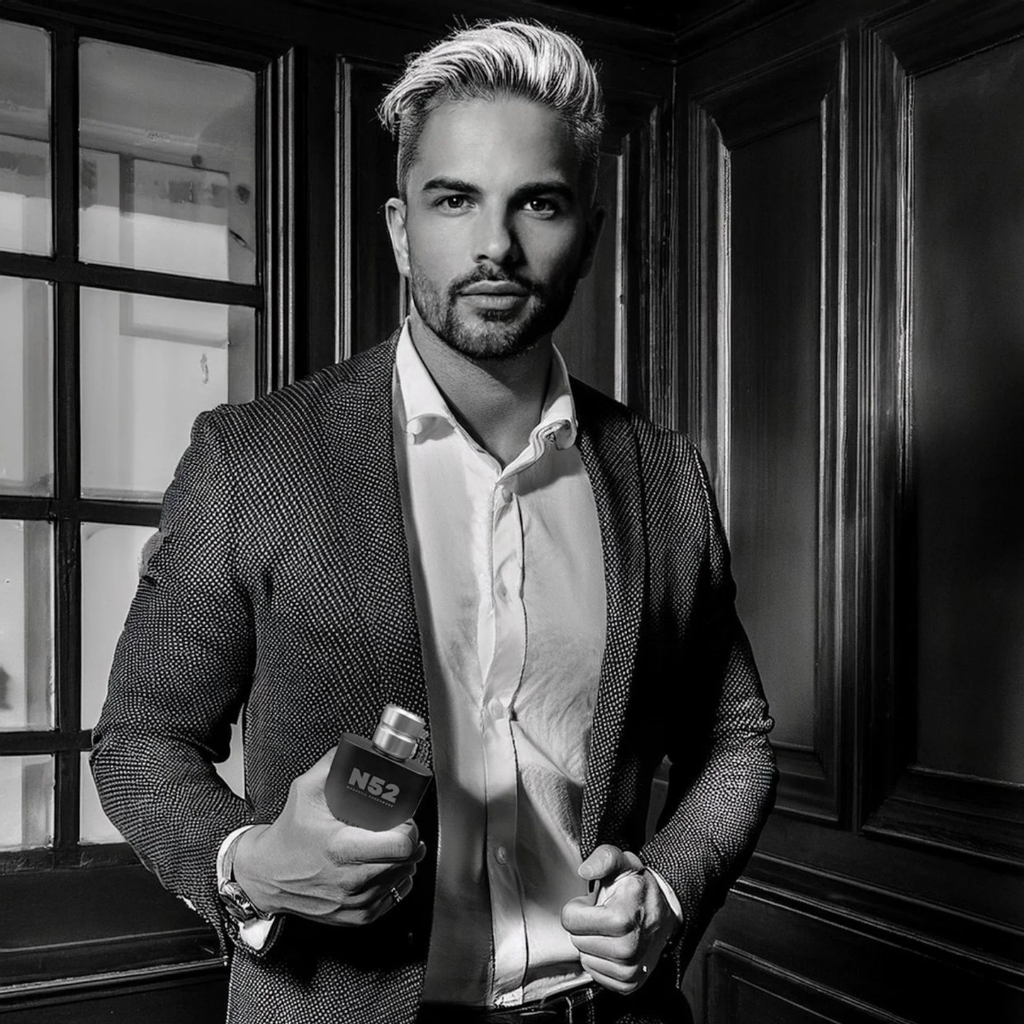 A black and white picture of a man black bottle of N52 Magnetic Pheromone Cologne by Eye of Love.