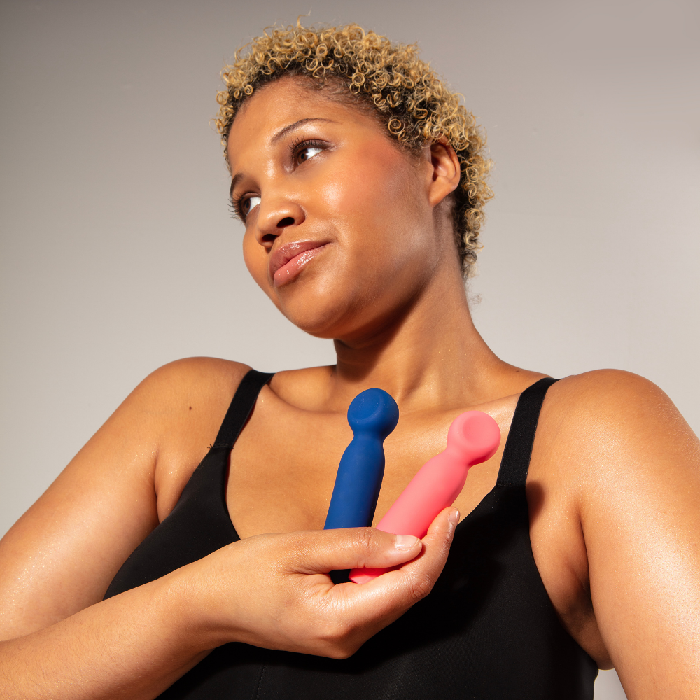 A lady holding a blue and a pink Vita Bullet Wand by Je Joue.