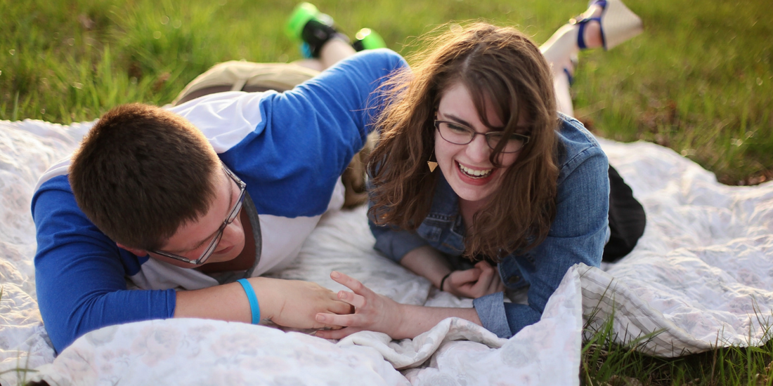 Couple laughing on a blanket outside