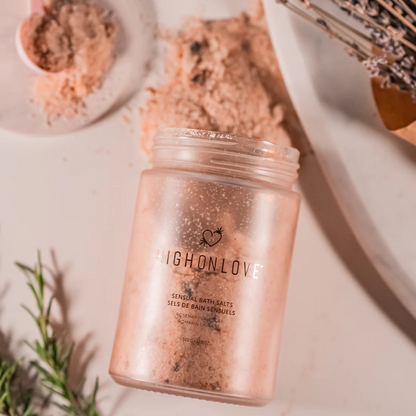 An open pink jar of Rosemary Lavender Bath Salts by High On Love spilling out.