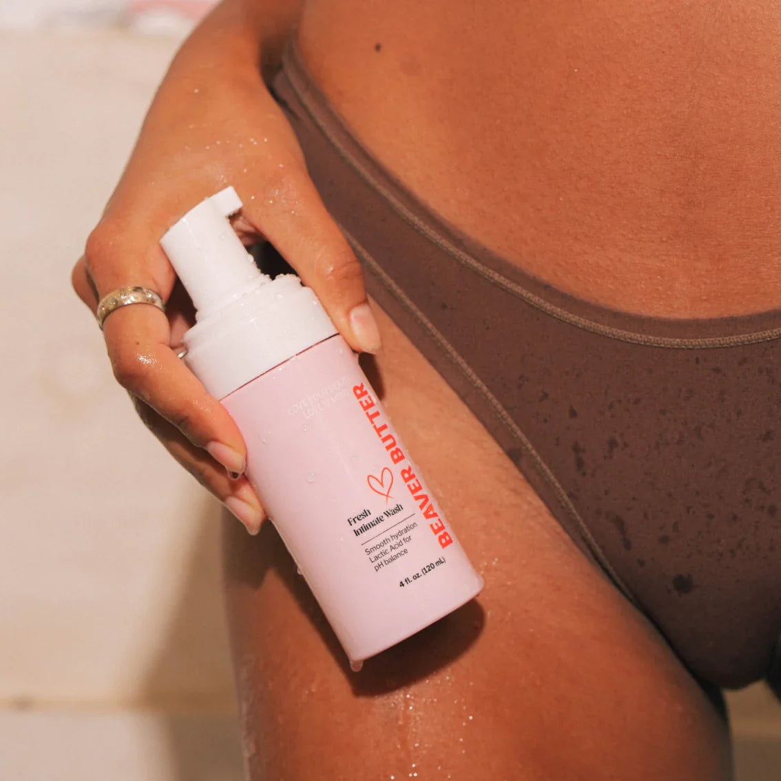 A pink bottle of Beaver Butter Intimate Wash by ECN held in the pelvic area by a woman.