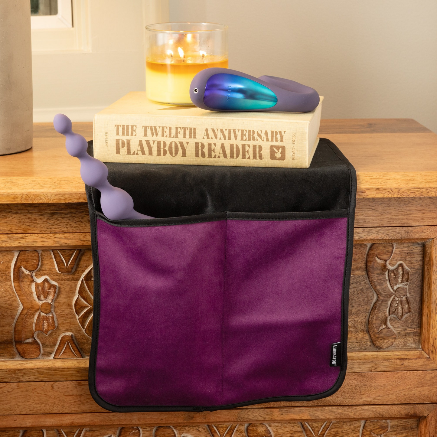An aubergine bed caddy by Fascinator sitting on a dresser holding a toy.