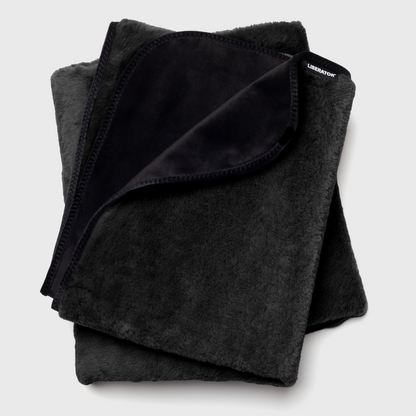 Folded black waterproof blanket on a light gray background