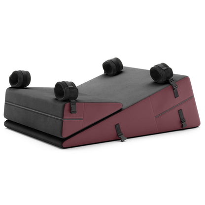 A set of Ultraleather raspberry Bondage ramp and wedge, Bedroom Furniture by Liberator with handcuffs on a white background.