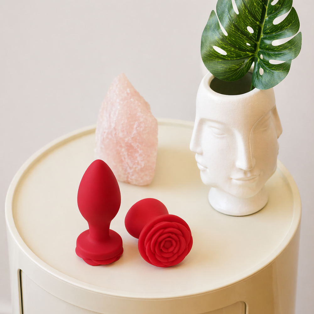 Two red Bouquet Anal Trainers in different sizes sitting on a white side table.