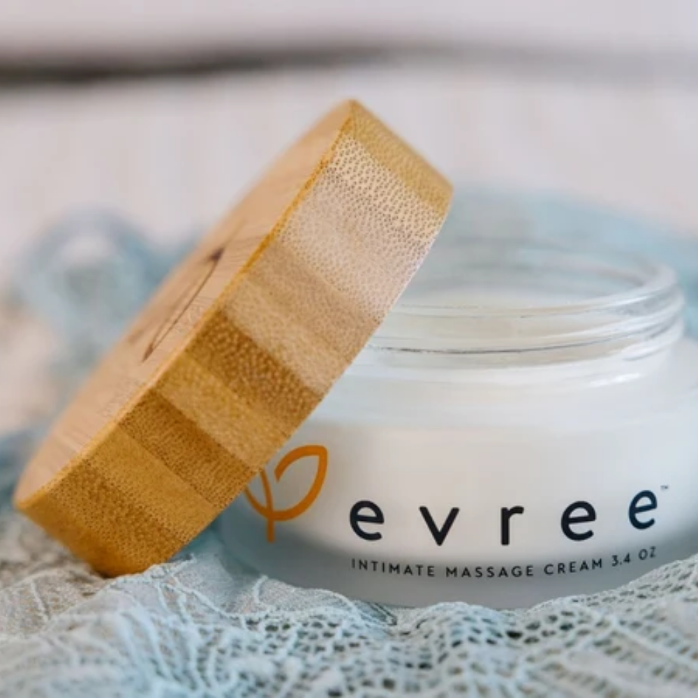 A white jar of Edible Massage Cream by Evree sitting open by the lid.