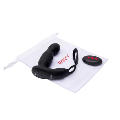 A black Thruster vibrating plug with an attached stamina ring next to the remote, sitting on the white bag.