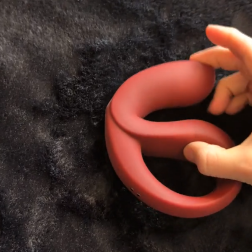 A red-colored Eros by Osuga being bent by a hand laying on a black blanket.