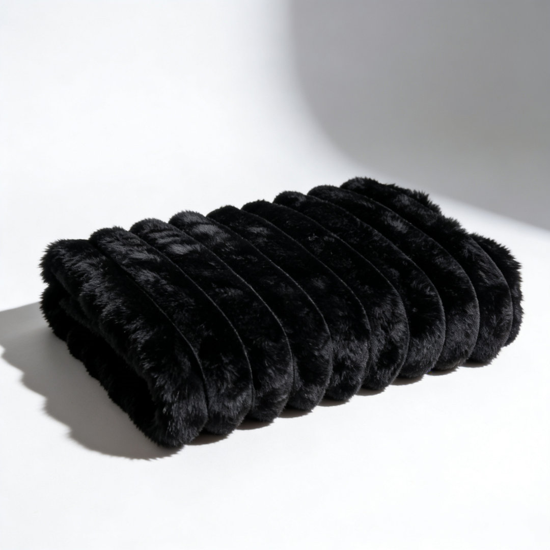 A black Fascinator Luxe Splashproof Fur blanket folded up against a white background.