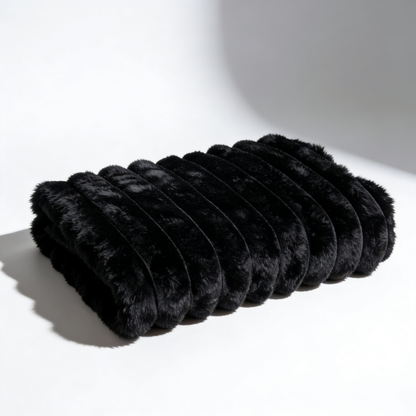 A black Fascinator Luxe Splashproof Fur blanket folded up against a white background.
