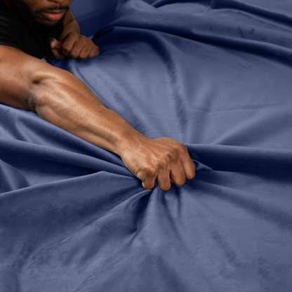 A hand grabbing a blue Fascinator Splashproof Throws, Bedroom Furniture by Liberator.