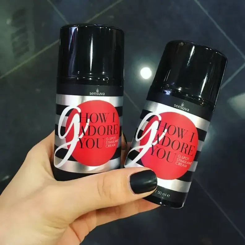 Two Sensuva G How I Adore you  enhancement cream product container with black lid and striped label being held by a hand.