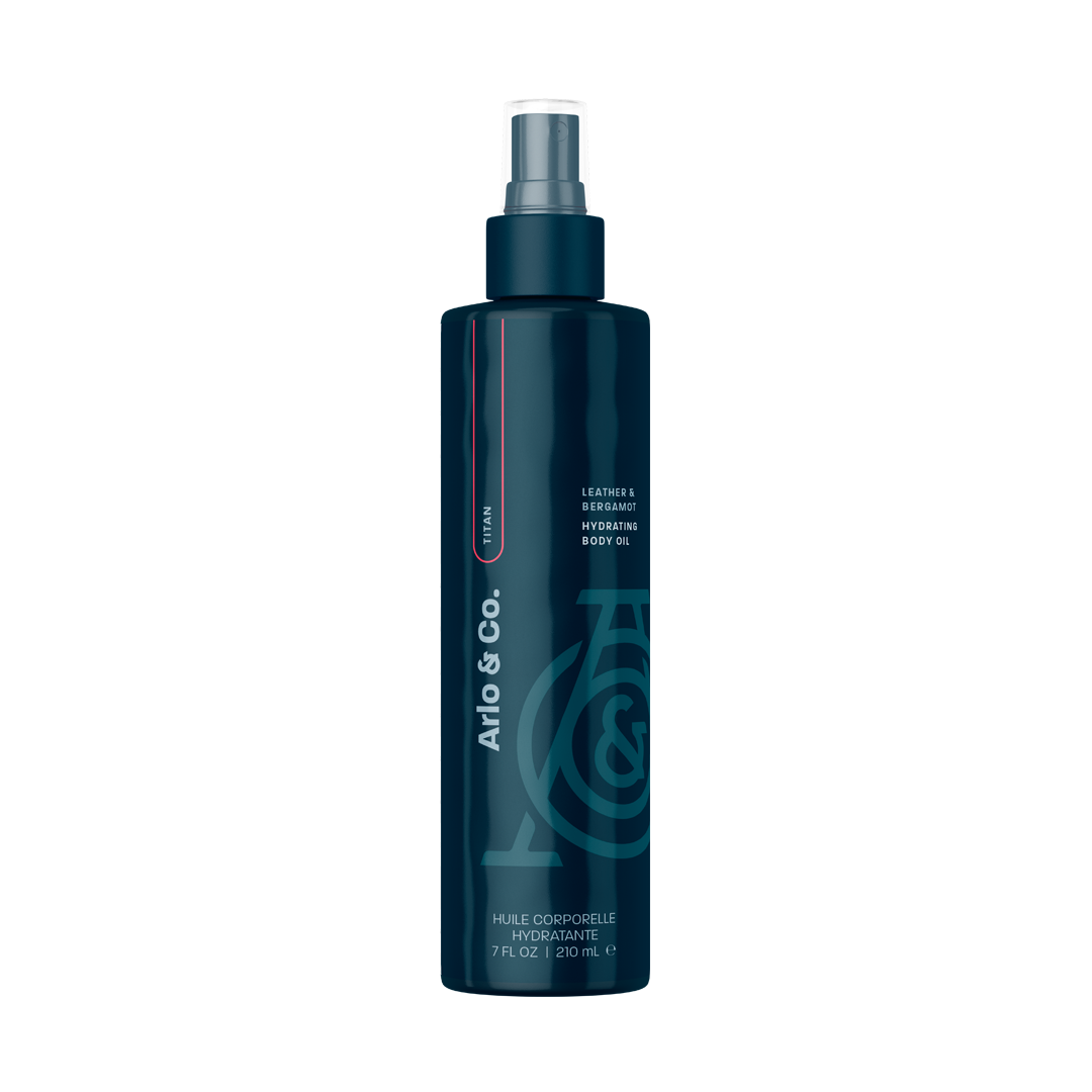A bottle of Lustra Hydrating Body Oil with a colorful design featuring various abstract shapes and a spray nozzle.