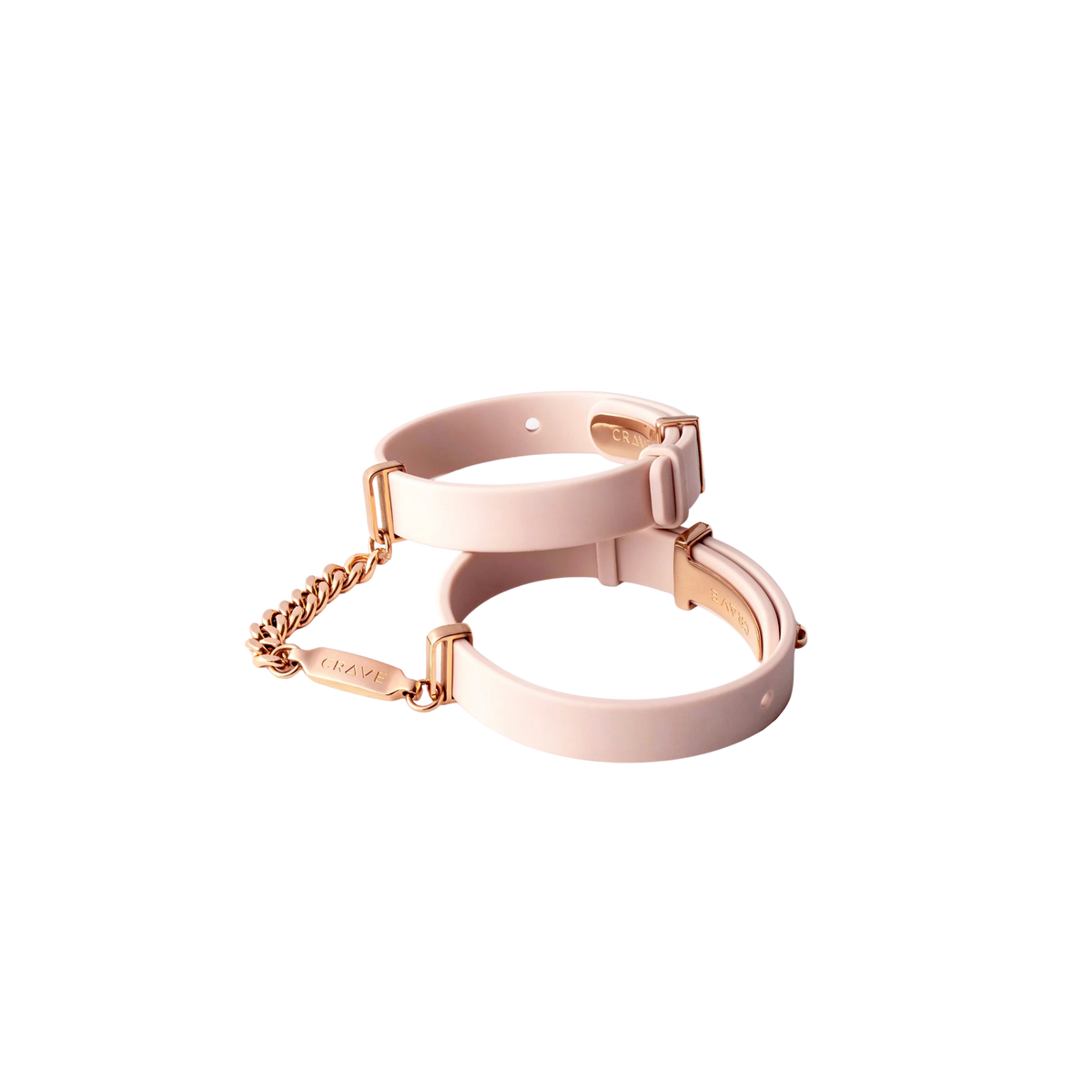 A set of light pink cuffs with a rose gold chain.