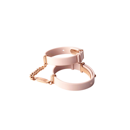 A set of light pink cuffs with a rose gold chain.
