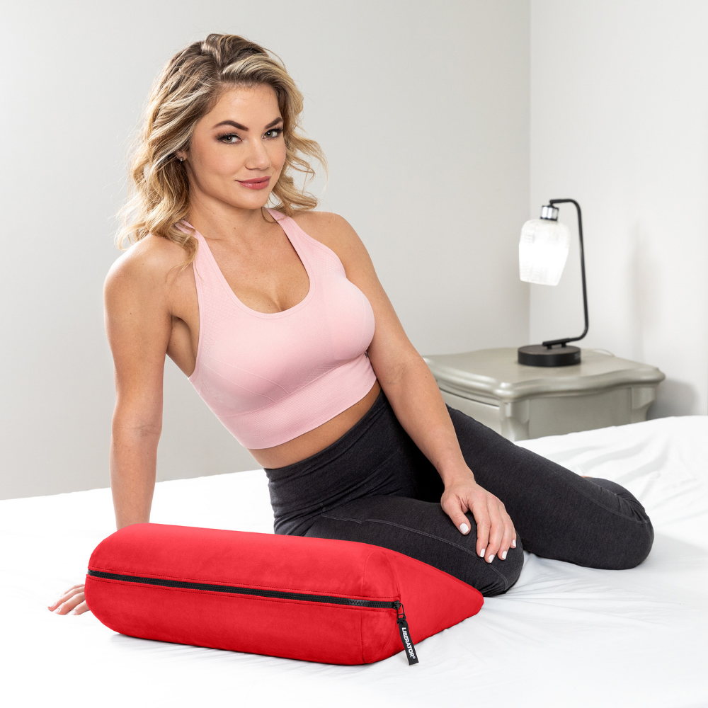 Woman sitting on a bed with a red Jaz positioning pillow