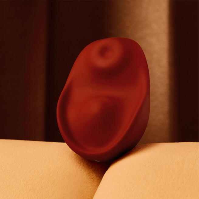 A red Kiss dual-tapping vibrator by Liberator sitting up.