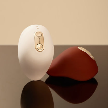 A white and a red Kiss dual-tapping vibrator by Liberator sitting on a table.