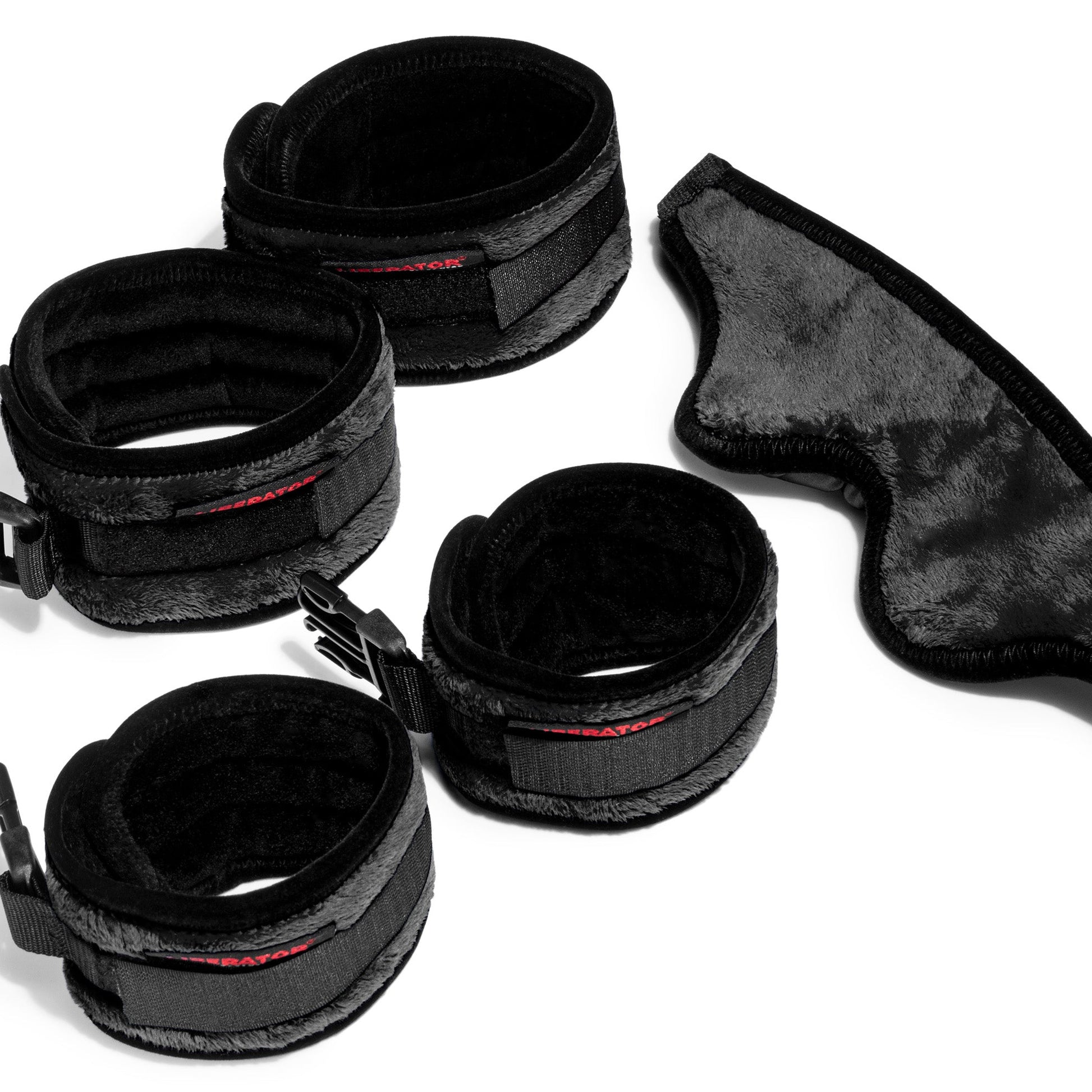 Four black cuffs and a blindfold for funiture by Liberator against a white background.