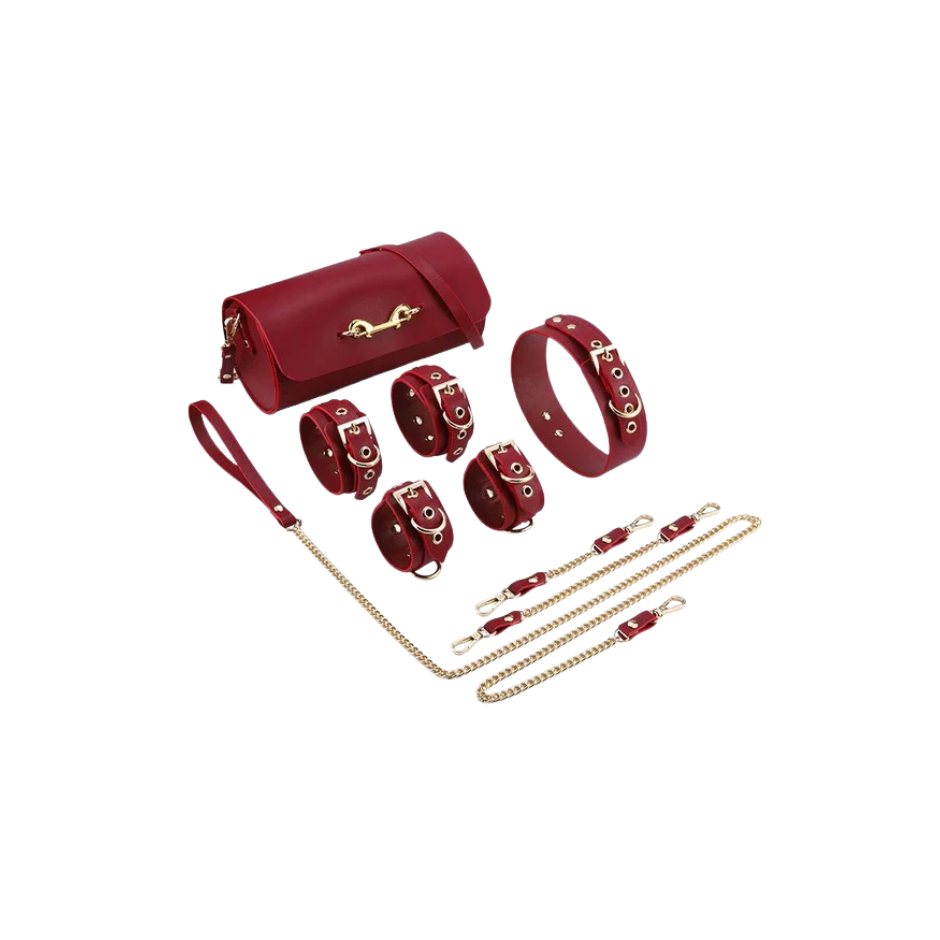 A red Luxe Bondage purse sitting next to four cuffs, a leash and collar.