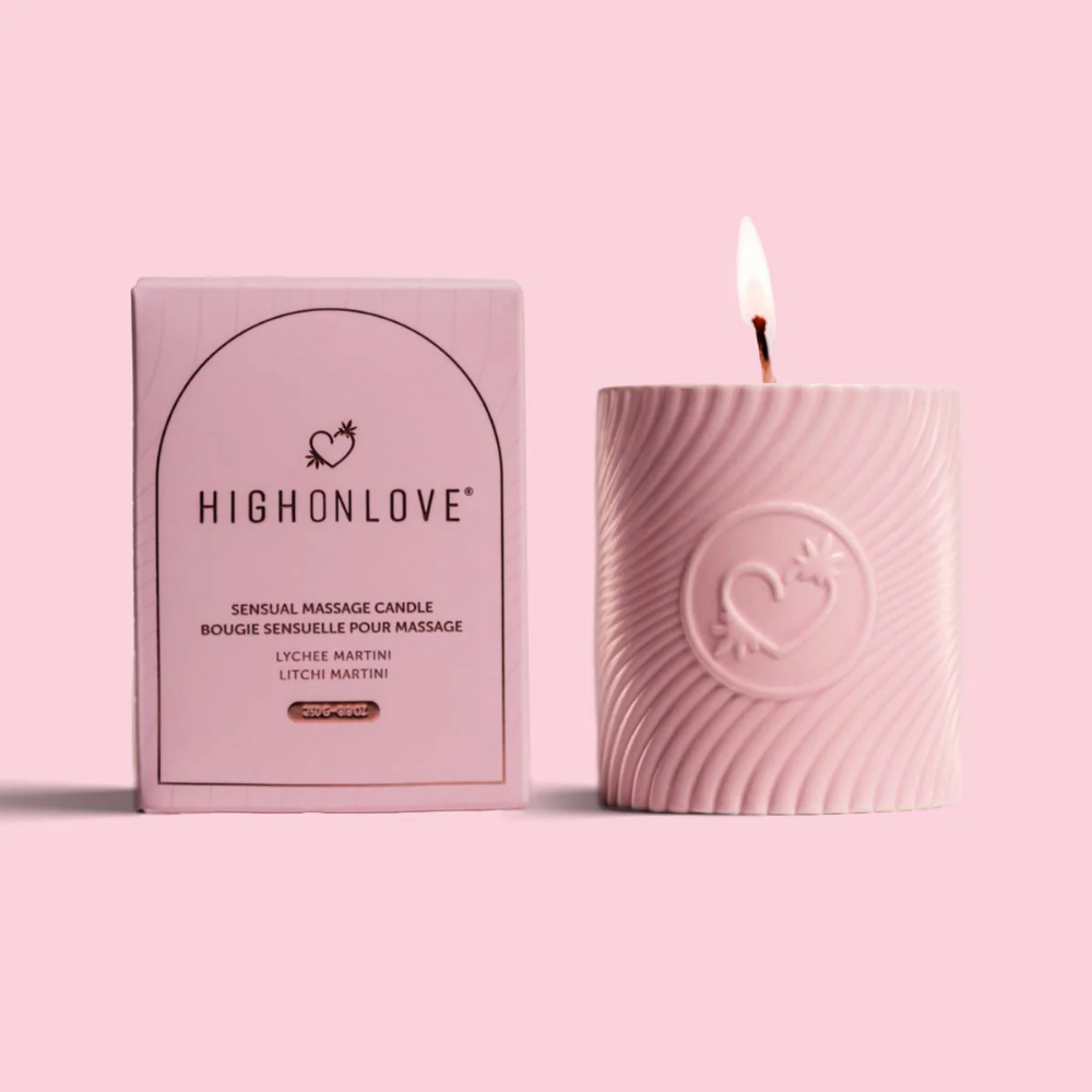 A pink massage candle mini by High On Love sitting next to its box against a pink background.