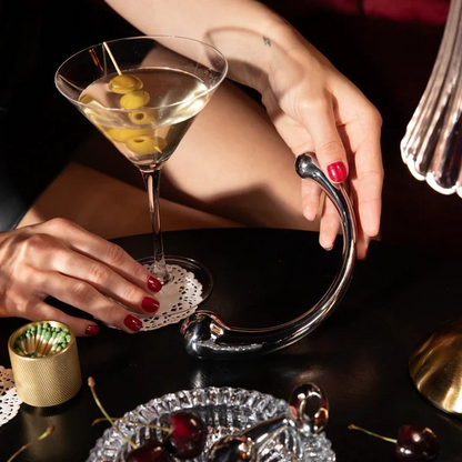 A stainless steel Mezzo wand on a table next to a martini glass.
