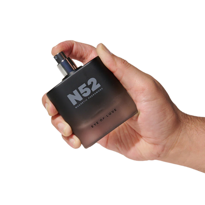 A hand holding a black bottle of N52 Magnetic Pheromone Cologne by Eye of Love.
