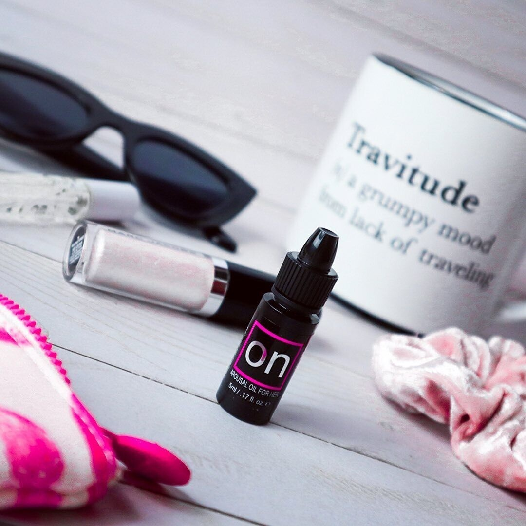 A small black bottle of ON Arousal Original Gel by Sunsuva sitting on a table with sunglasses and a few other things.