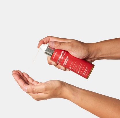 A hand using a bottle of Matchmaker Red Diamond Pheromone Body Oil by Eye of Love against a white background.