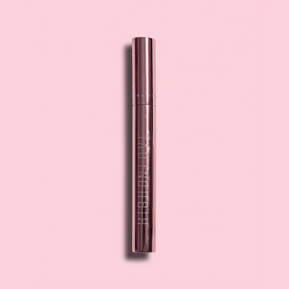 A tube of Plumping Lip Gloss by High On Love against a pink background.