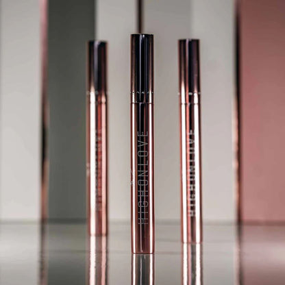 Three tubes of Plumping Lip Gloss by High On Love against a pink and grey background.