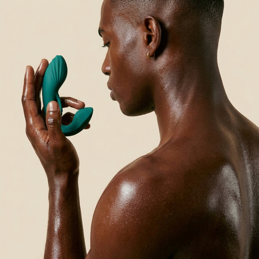 A man holding a green Prove Prostate Vibrator by Liberator.
