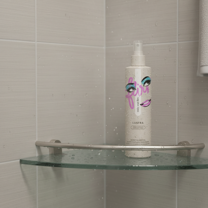 Lustra body oil bottle sitting on a glass shower shelf with water droplets.