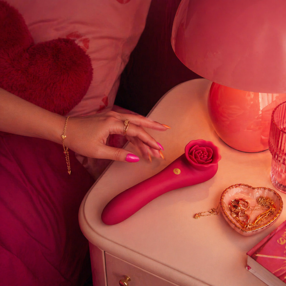 A red rose colored Rose Quake vibrator with a rose end sitting on a bedside table.