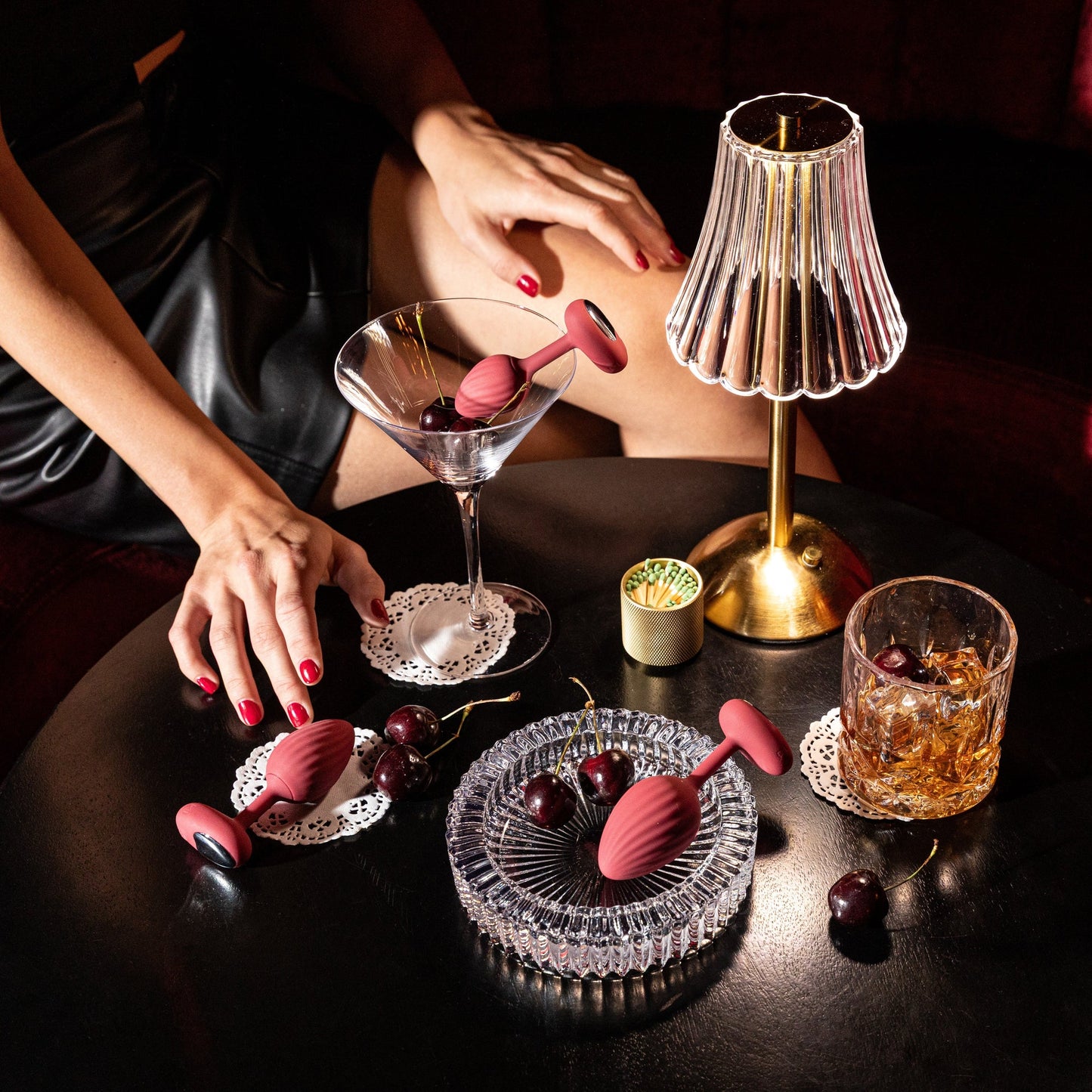 A set of three red graduated Rouge backdoor plugs sitting on a table with drinking glasses and a lamp.