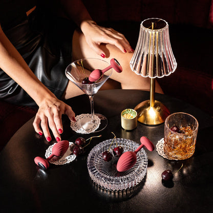 A set of three red graduated Rouge backdoor plugs sitting on a table with drinking glasses and a lamp.