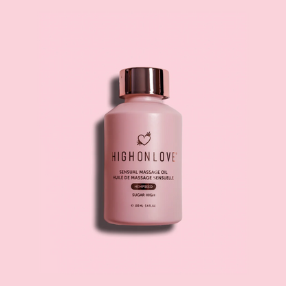 A pink bottle of Sugar High Massage Oil by High On Love against a pink background.