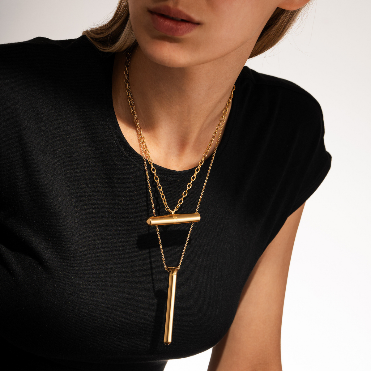A lady wearing a 24k Gold Vibrator Necklace from the Tease Collection and a Vesper vibrator necklace.