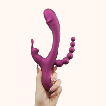 A hand holding a purple Trilux vibrator against a white background.