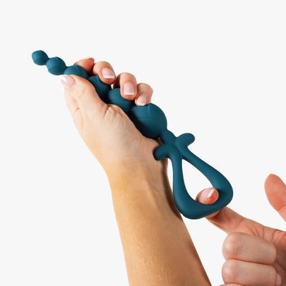Teal blue anal beads held by a person on a white background