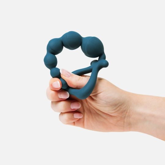 Hand holding a blue silicone anal beads against a white background