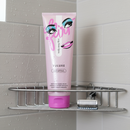 Vuluxe shaving cream in a Flirt scent next to a razor in a shower.