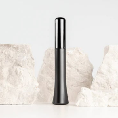 A Wink discreet vibrator in Gun Metal Black with a white background with rocks on it.