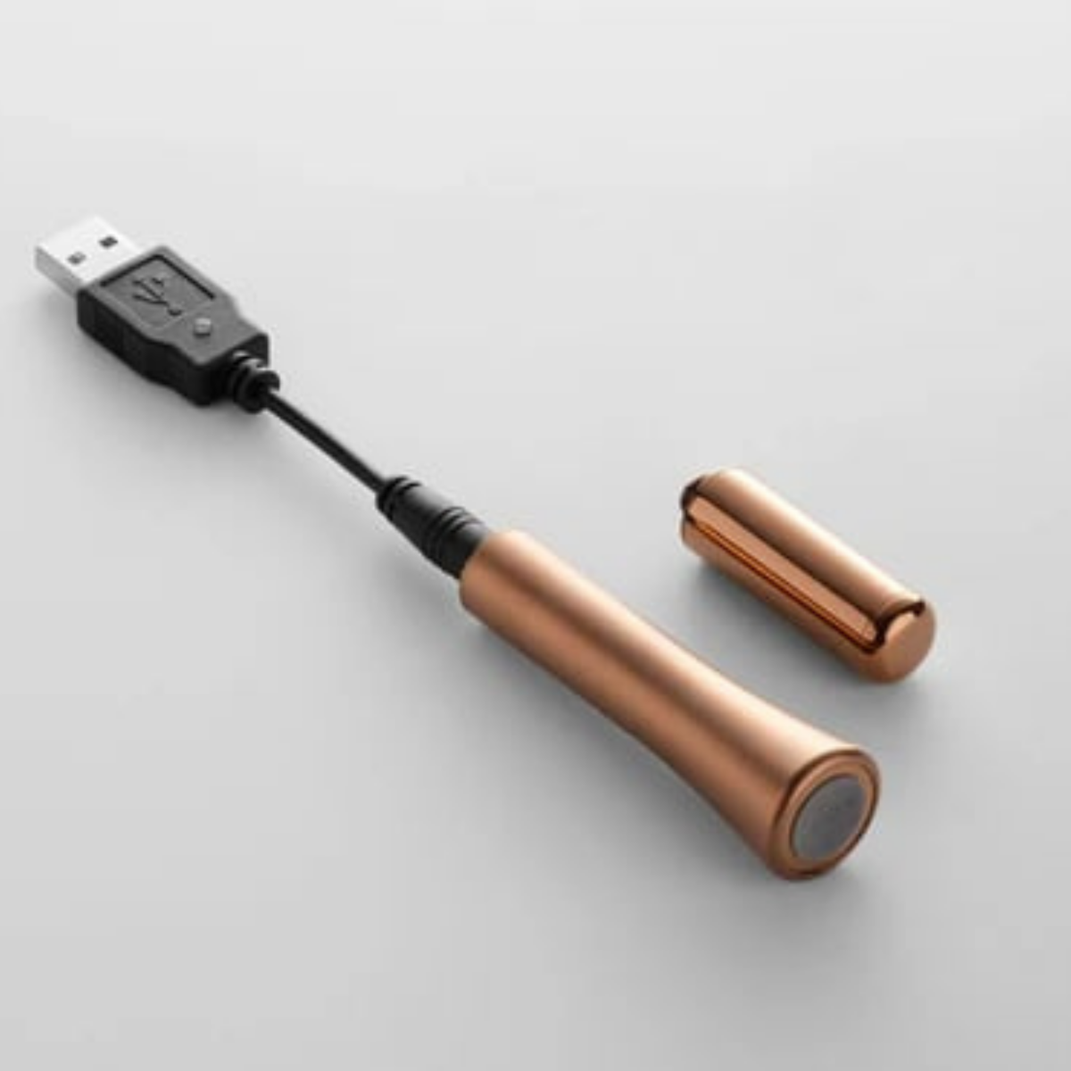 A Wink discreet vibrator in rose gold with the charger attached.