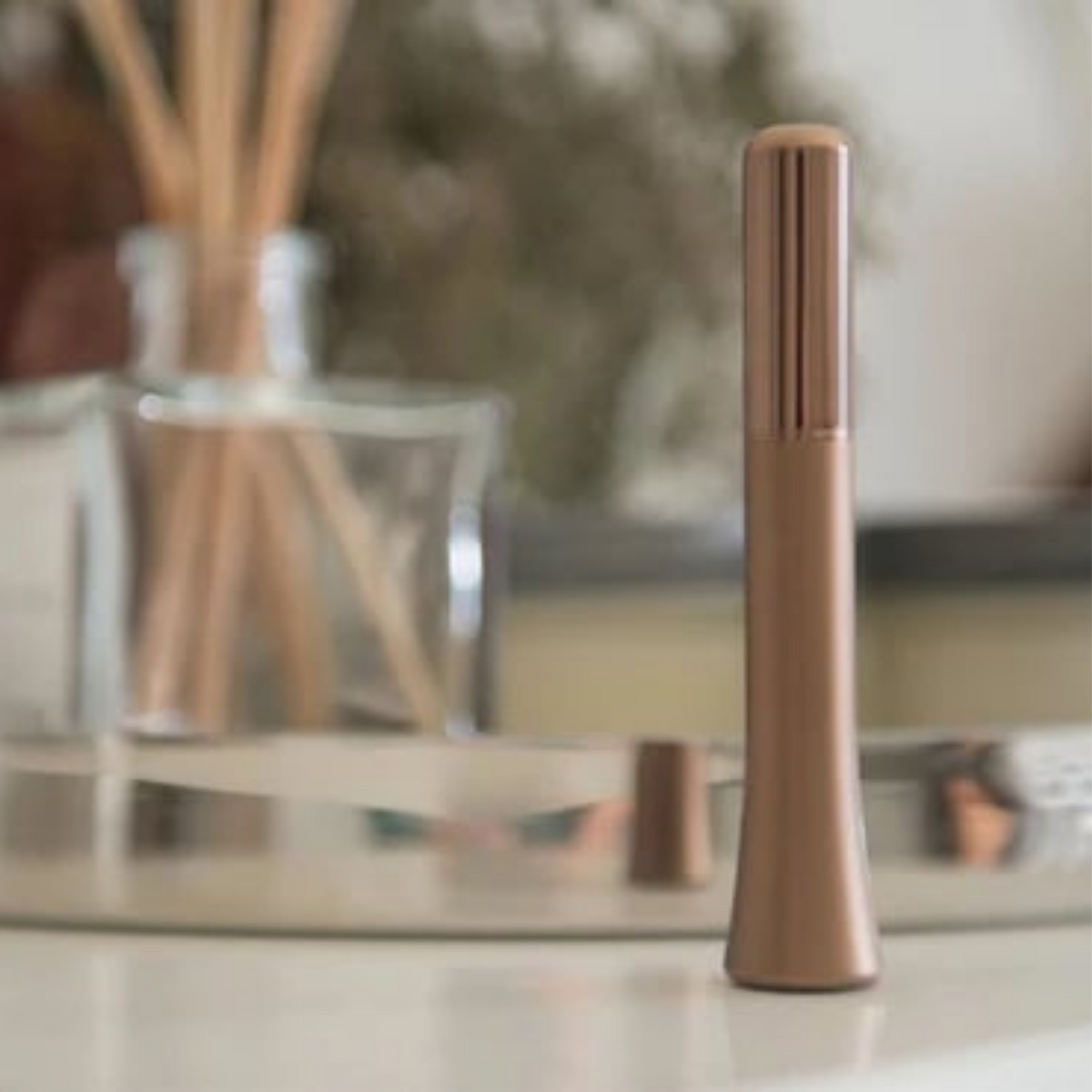 A Wink discreet vibrator in Rose gold sitting on a table.
