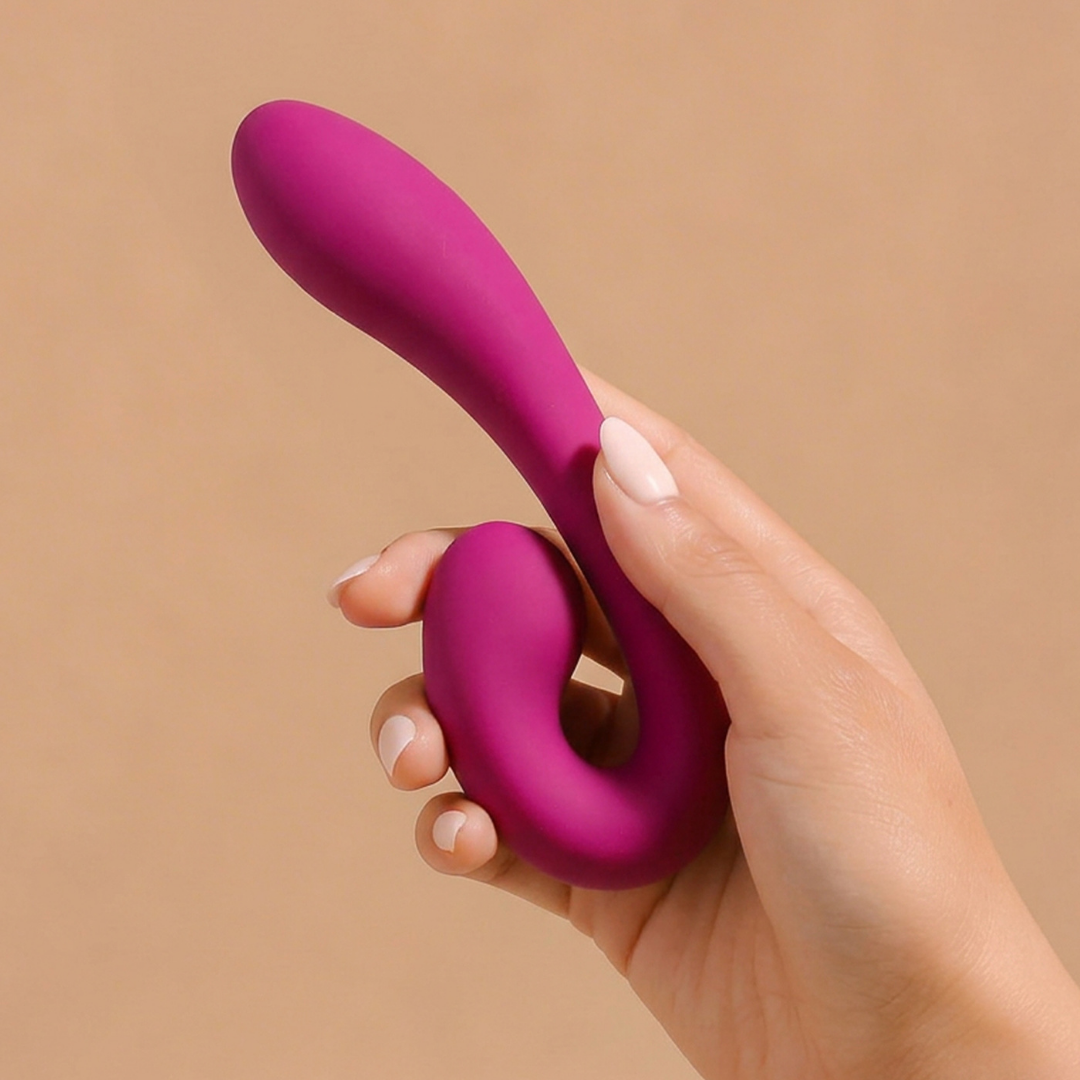 A hand holding purple Zya Vibrator against a tan background.