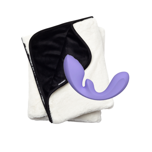 Folded black and white fascinator waterproof blanket with a purple curved Flow g-spot toy on a white background